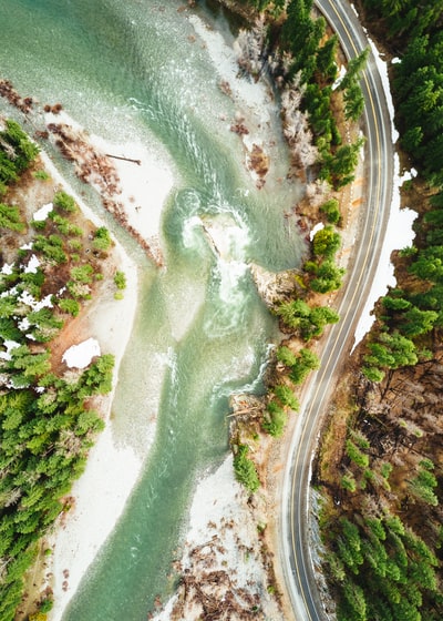 白天河流附近山坡上空柏油路的航空摄影